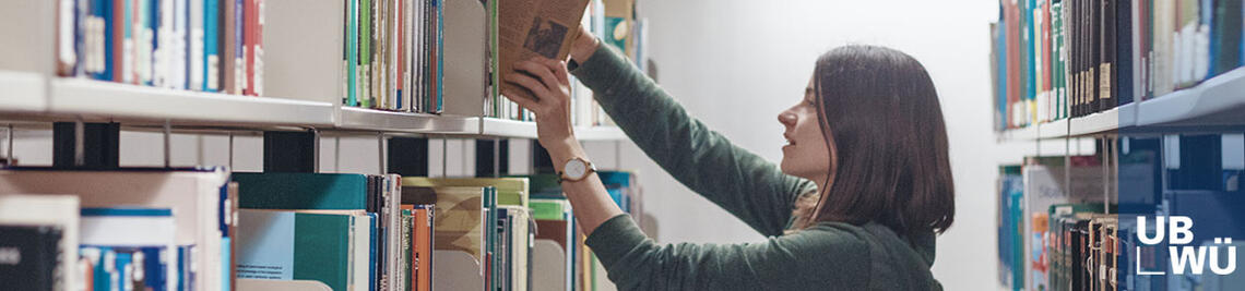 Studentin holt Bücher aus einem Regal in der Bibliothek